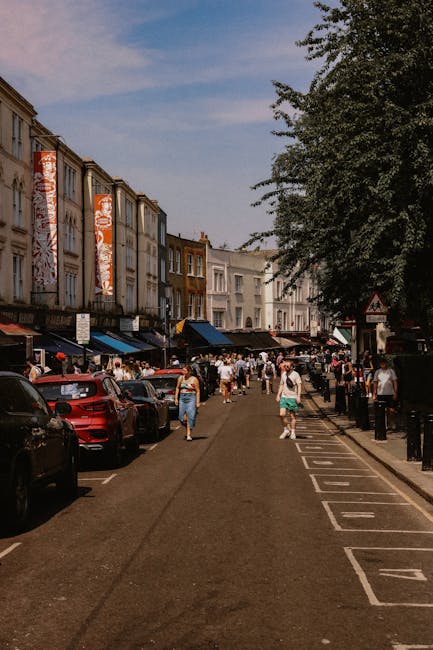 A black London taxi is parked on the street in front of a row of residential Victorian-style terraced houses with ornate white facades, large windows, and small balconies. The houses are painted in pa